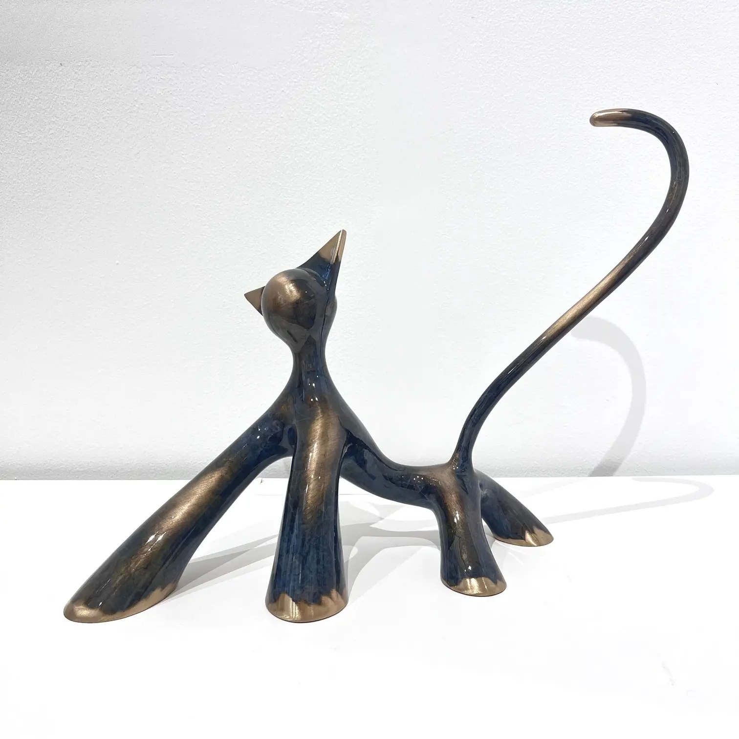 Sculpture féline noire et grise brossée meulée, queue haute, contrastes mats et brillants, posture assurée.