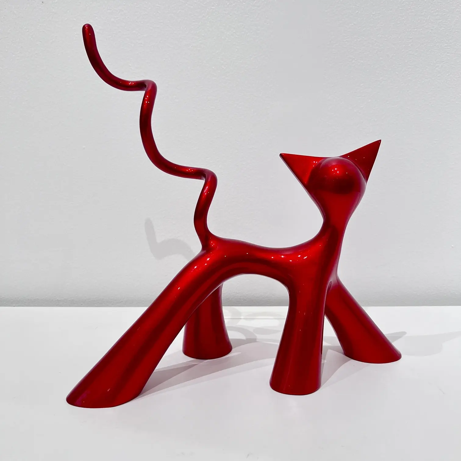 Sculpture rouge candy brillant, silhouette ramassée, courbes gourmandes et finition laquée éclatante.