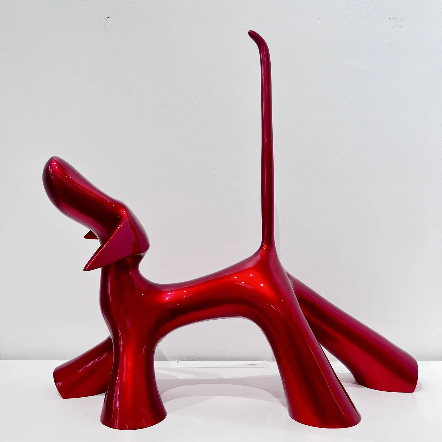 Sculpture rouge candy brillant, volumes généreux, queue levée, surface laquée éclatante et posture festive.