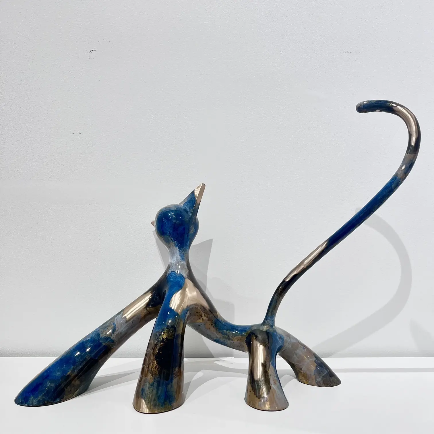 Sculpture féline allongée, finitions meulées, effets noir et gris brossé meulé, silhouette dynamique et queue courbe