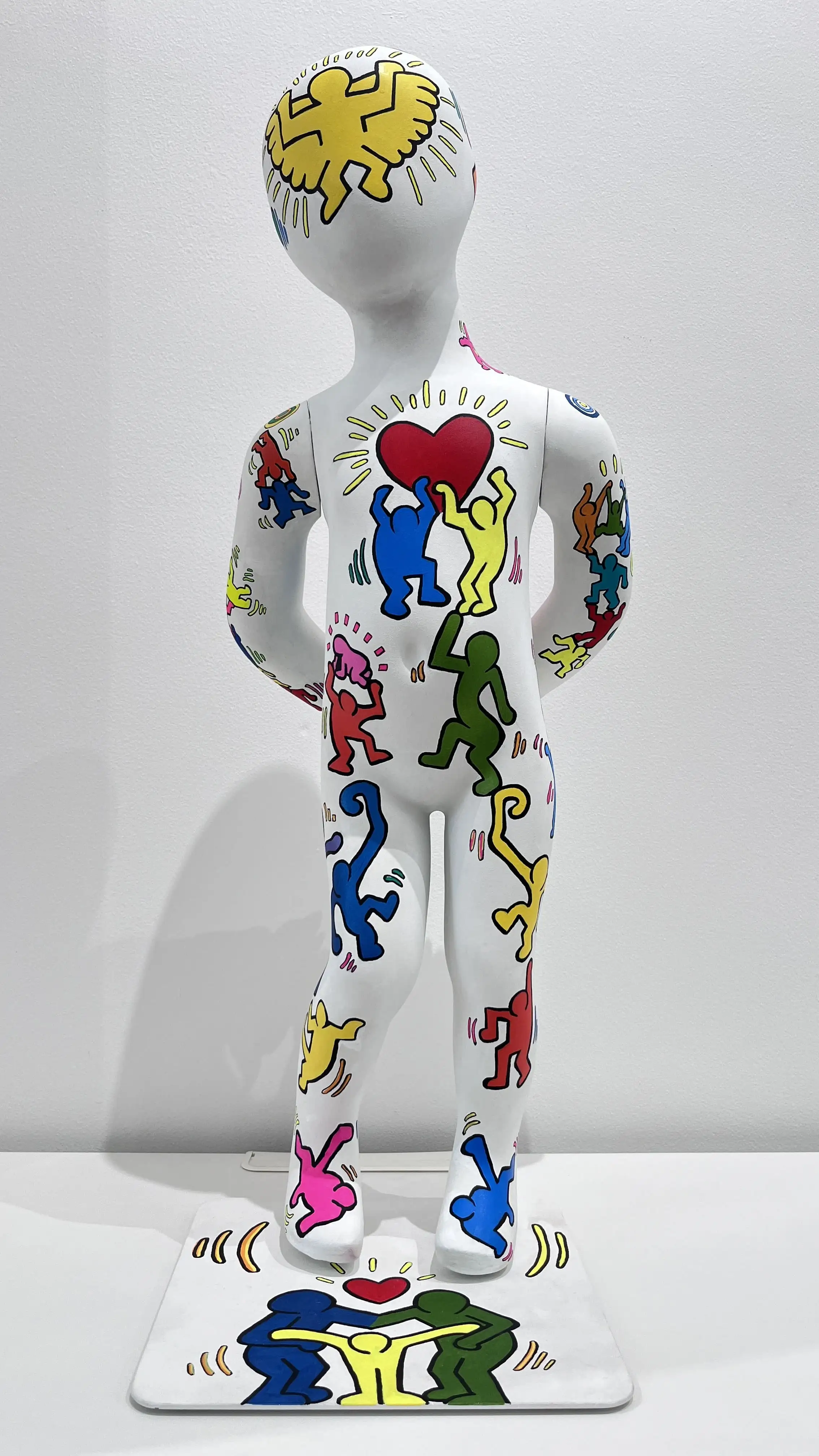 Sculpture enfant blanc peint de figurines colorées façon pop art, cœur rouge