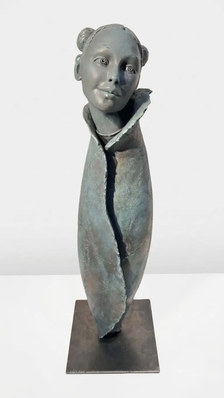 Sculpture en grès aux tons bleus et gris, visage féminin expressif enveloppé dans une forme textile organique aux textures brutes.