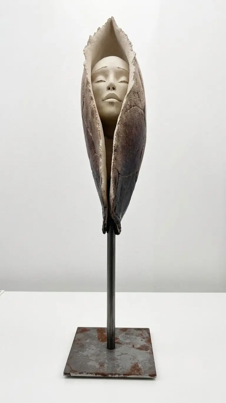 Sculpture en grès blanc représentant un visage serein émergeant d'une forme organique sur socle en métal noir minimaliste