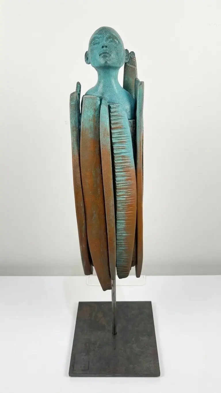Sculpture en grès aux dégradés bleus et ocres, visage serein entouré de formes verticales incisées évoquant une protection.