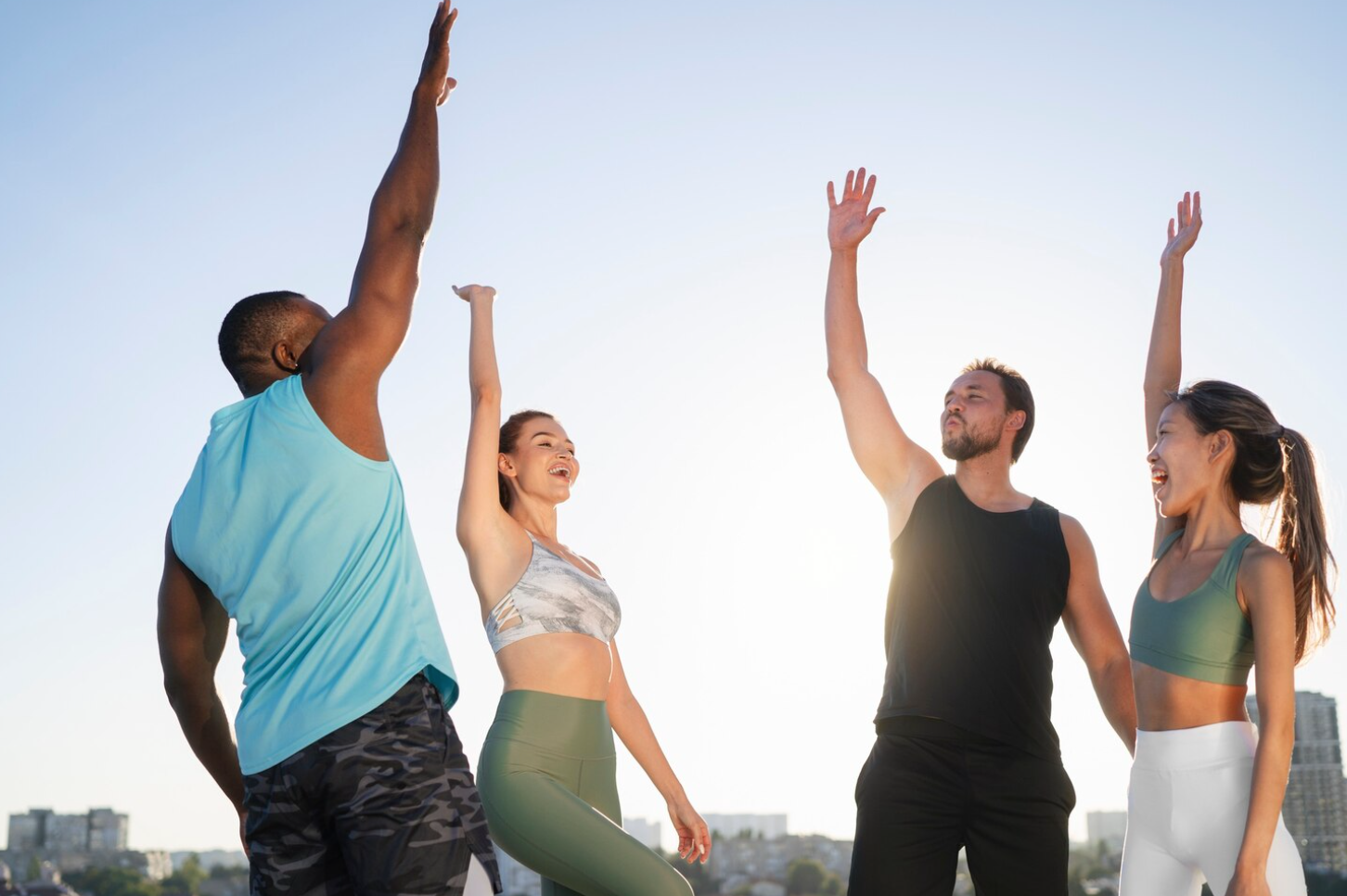A group of four people looking fit and healthy and celebrating by raising their right hands