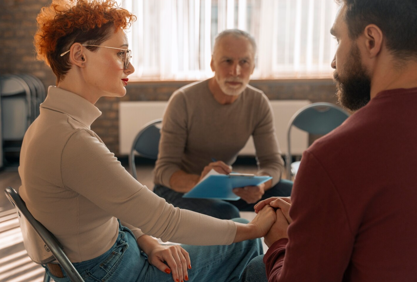 Two people participating in a supportive therapy session with a counselor, highlighting healing during addiction recovery