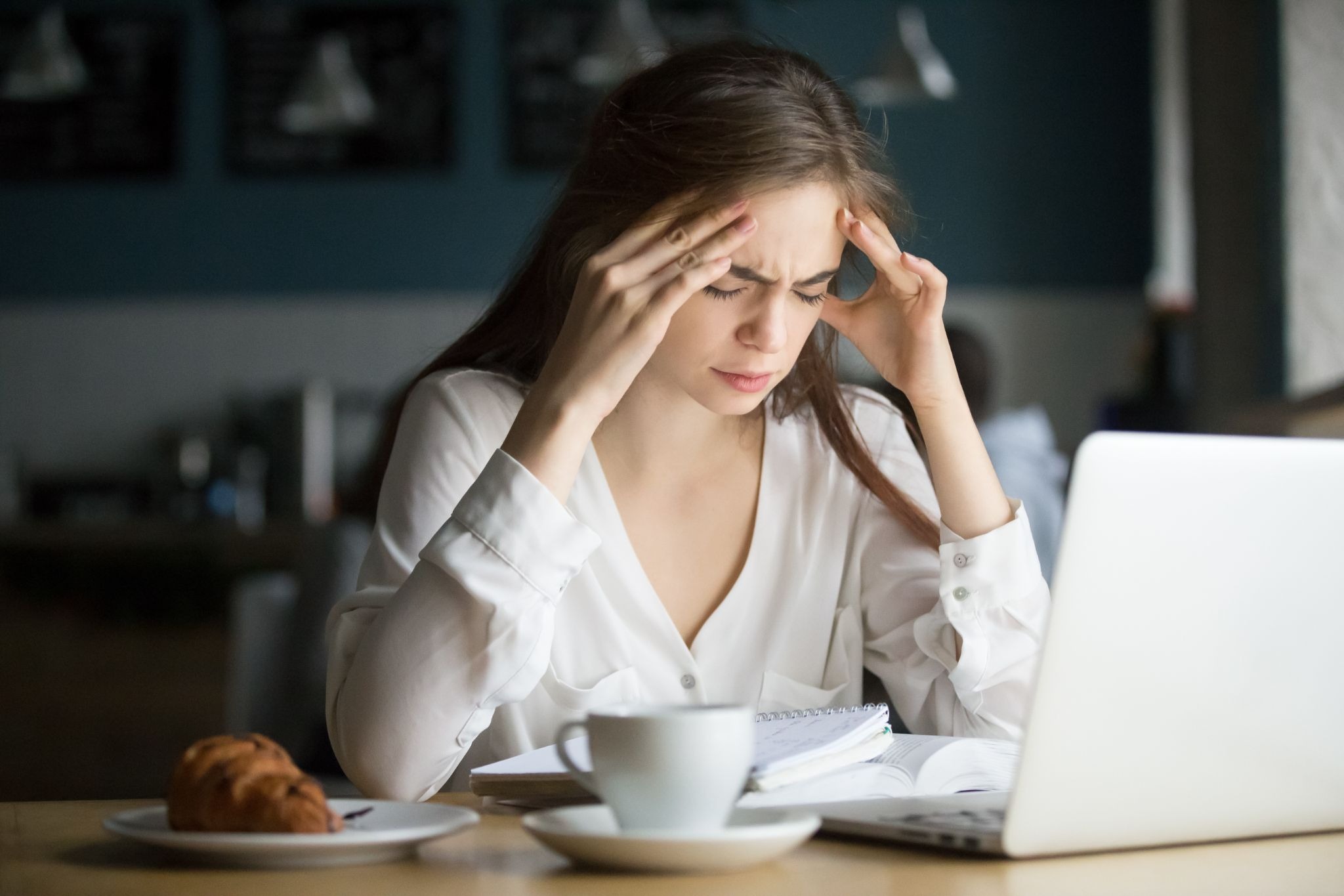 A woman experiencing stress and anxiety while sitting at a table with a laptop and notebook, representing the emotional challenges of benzodiazepine withdrawal