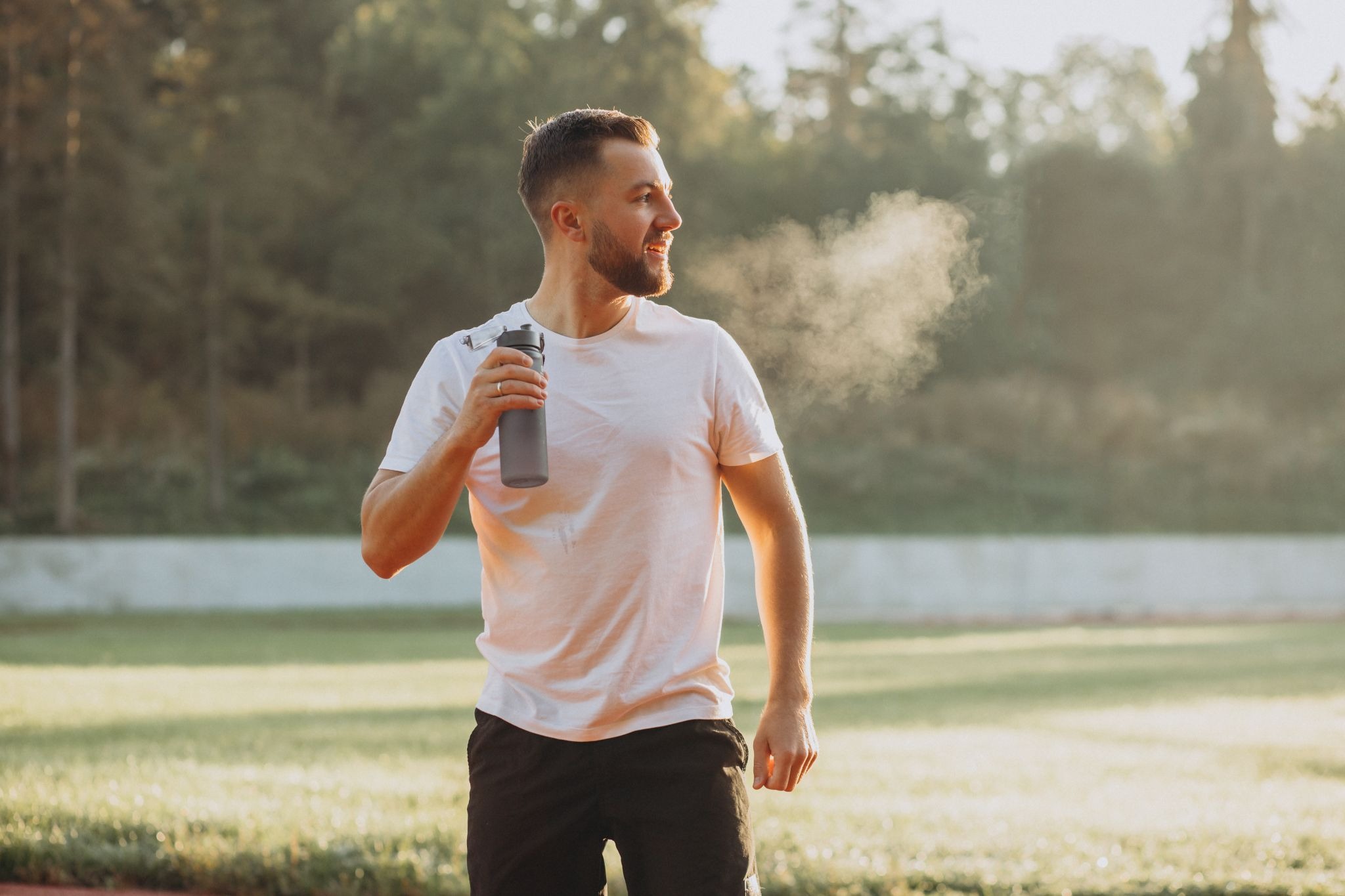 Man outdoors drinking water after exercise, symbolizing healthy routines and physical wellness during substance recovery