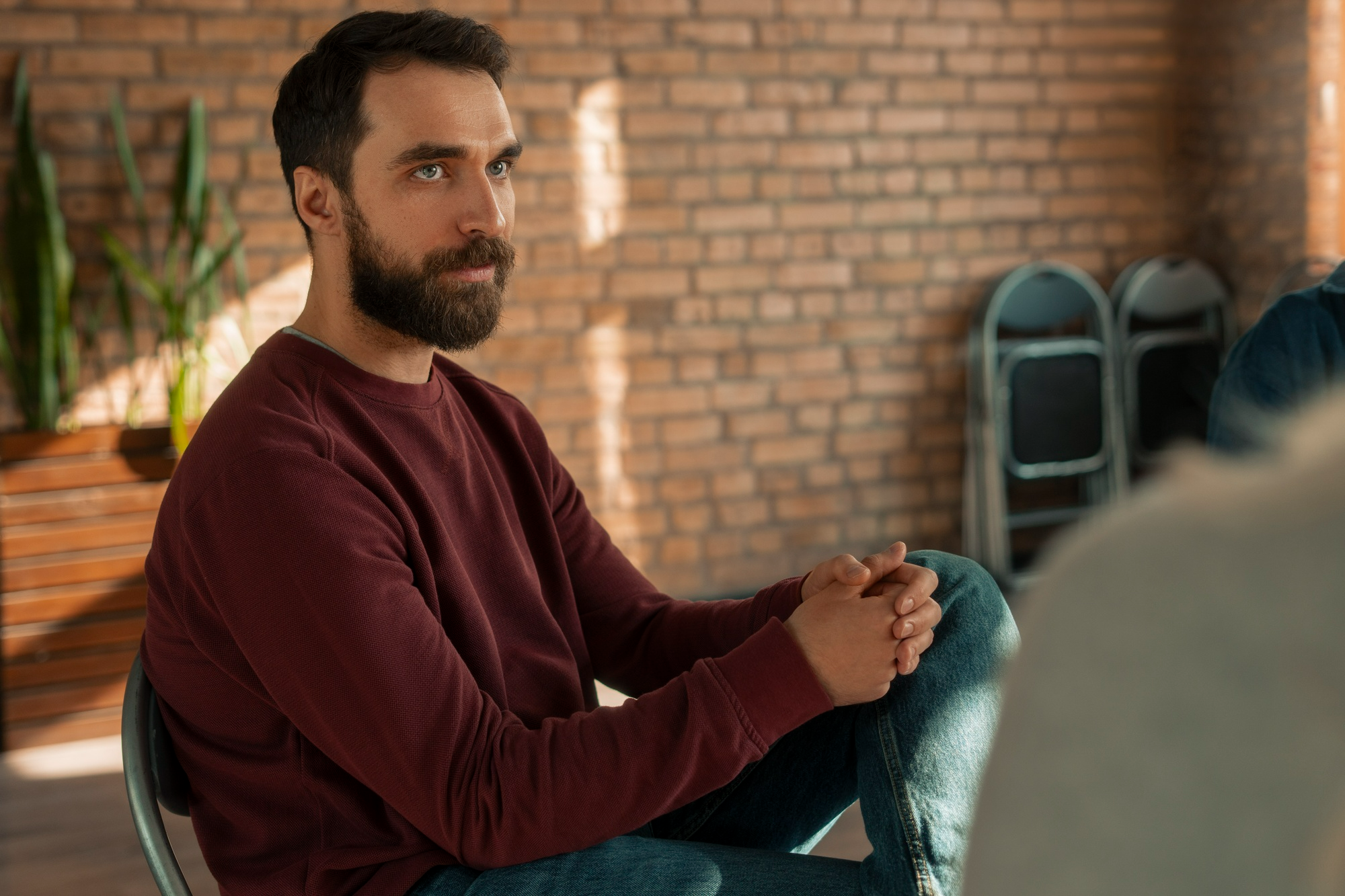 A man listens attentively during a support group for meth addiction recovery.