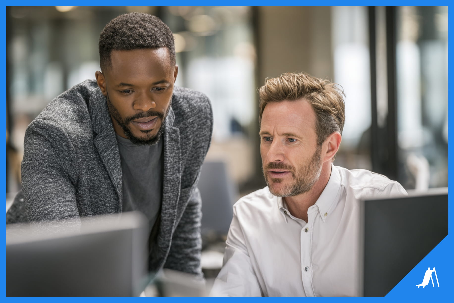 Two team members collaborating at a computer in a shared workspace