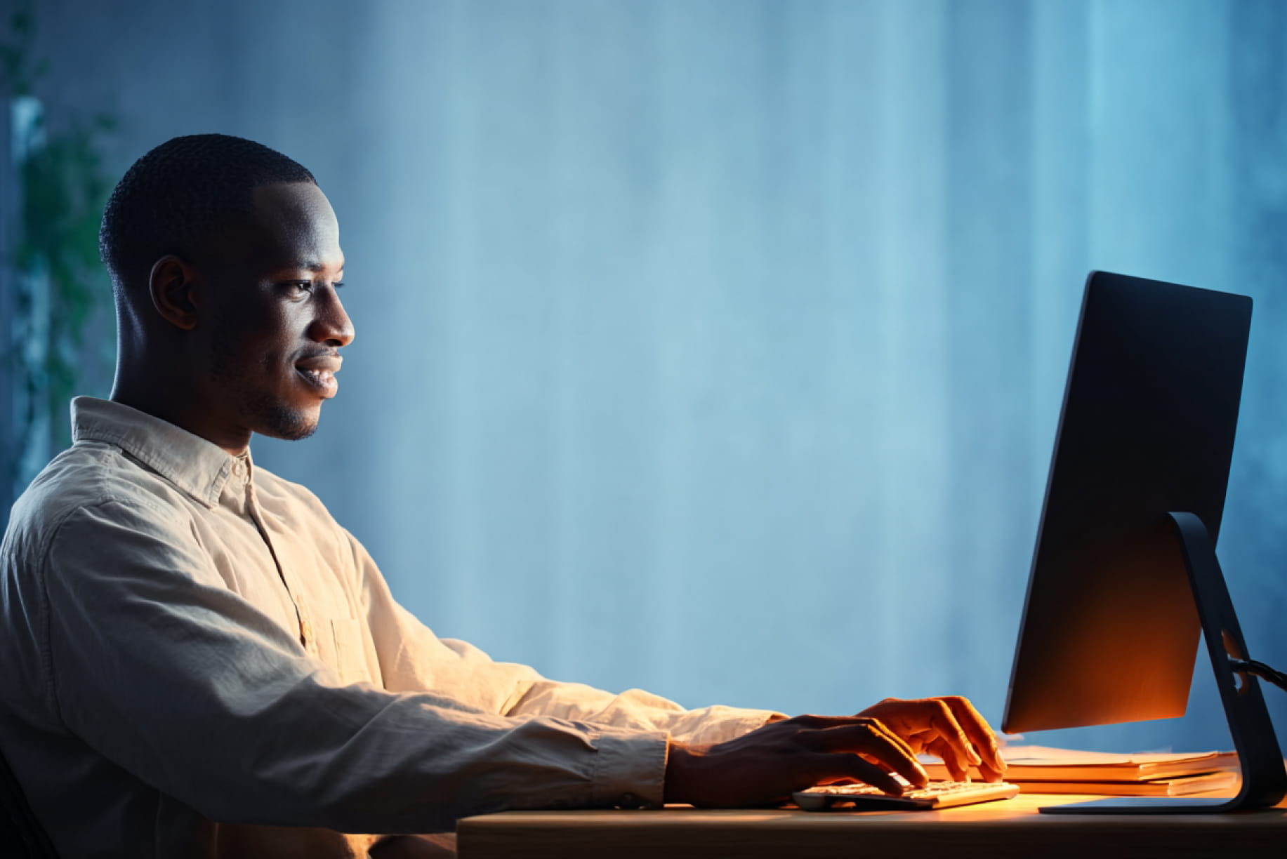 Professional working at a desktop computer in a softly lit office environment, representing building sustainable GEO authority through consistent digital strategy