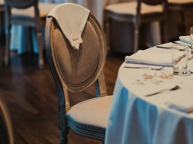 An empty reserved chair at a set wedding reception table