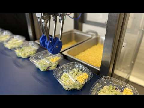 Chef robot placing corn into a small insert