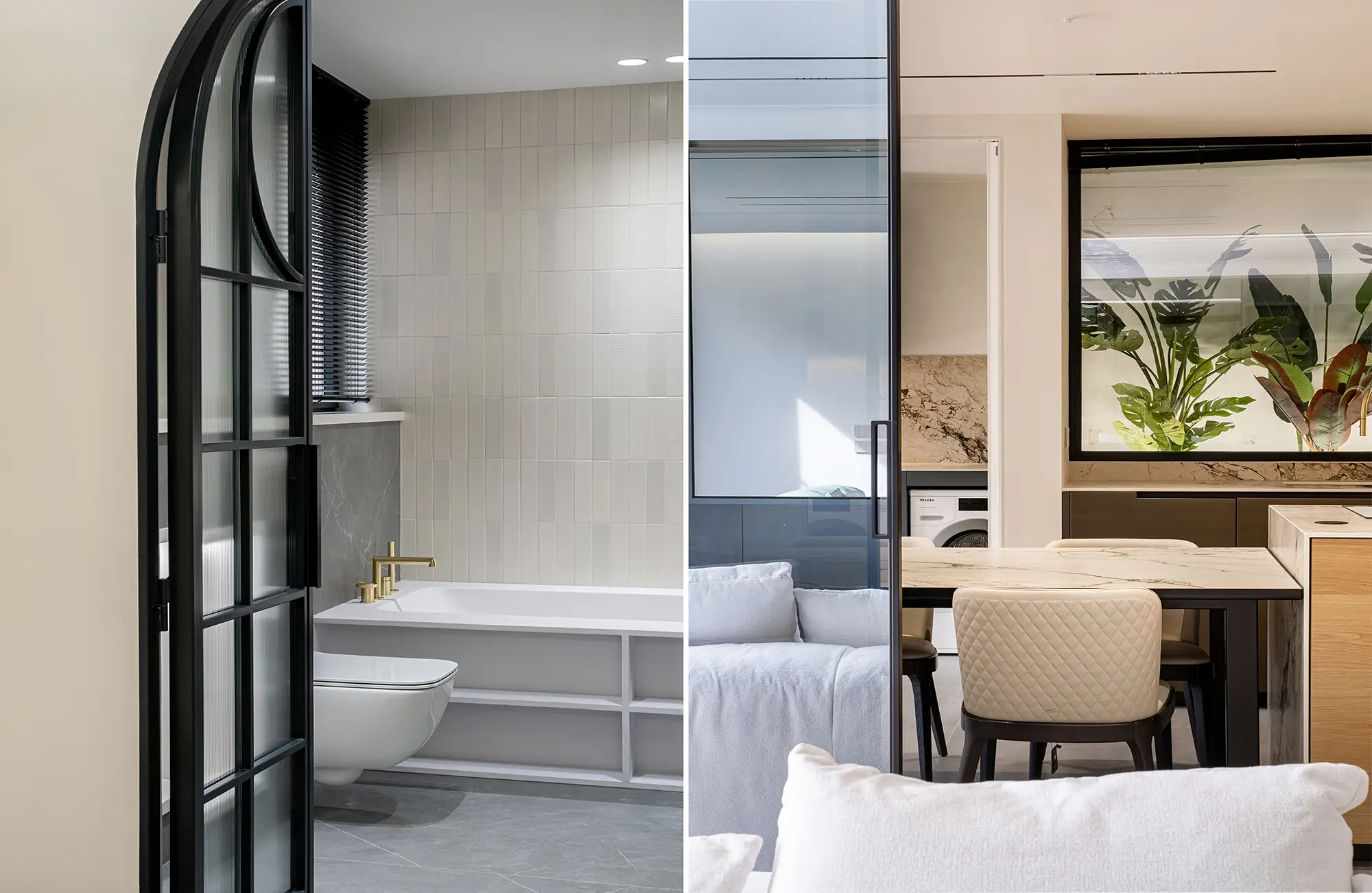 Vista interior dividida. A la izquierda, un baño moderno con azulejos gris claro, una bañera empotrada y grifería dorada, enmarcado por una puerta arqueada de metal negro. A la derecha, un comedor elegante con mesa de mármol y sillas, iluminado por una ventana grande que presenta arte con motivos de plantas tropicales.