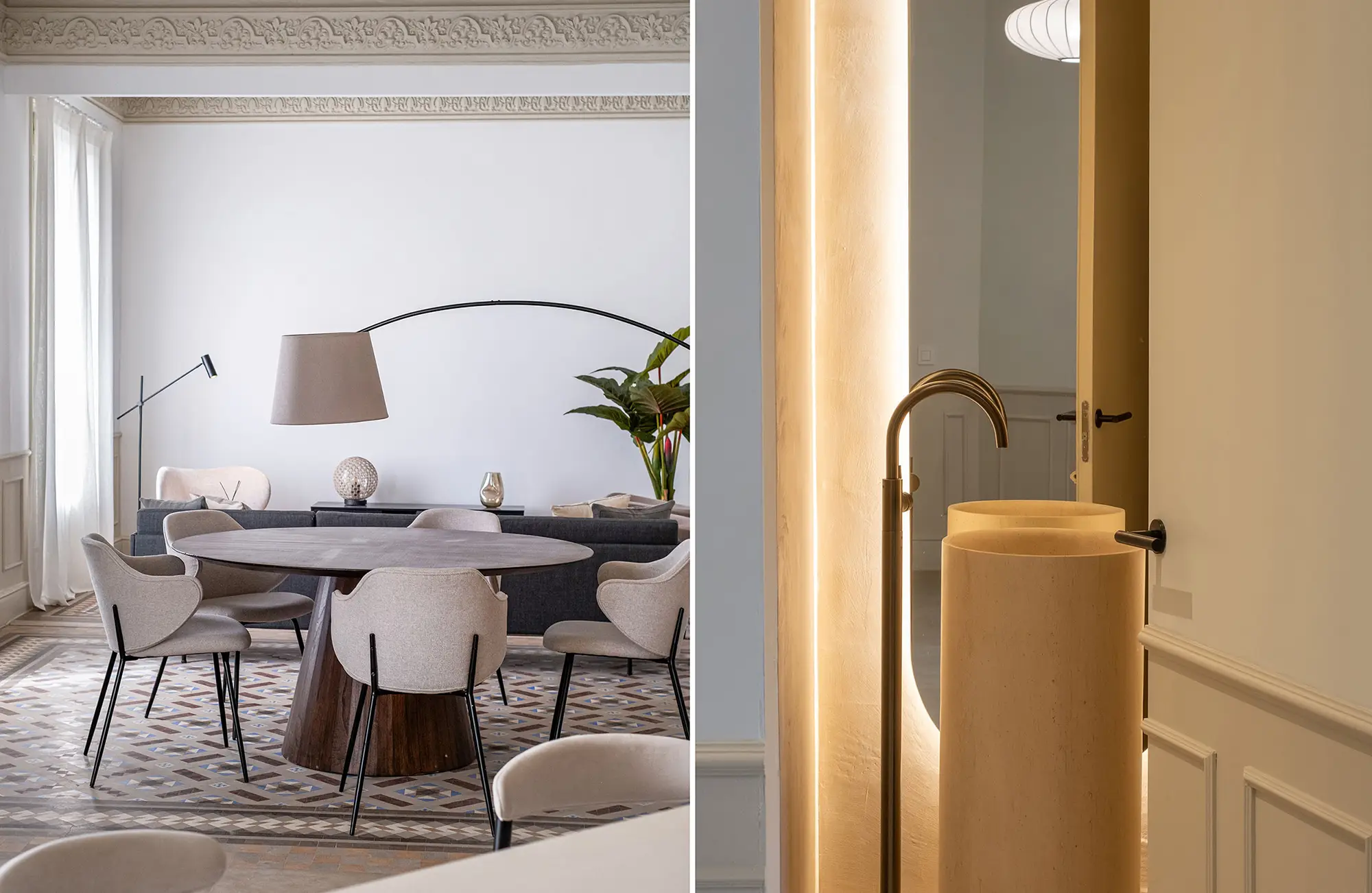 Espacios divididos de comedor y baño. A la izquierda, un comedor con sillas beige y una mesa redonda de madera sobre un suelo de patrones intrincados, con una gran lámpara de arco. A la derecha, un baño minimalista con un lavabo escultórico de piedra y cálida iluminación de acento.