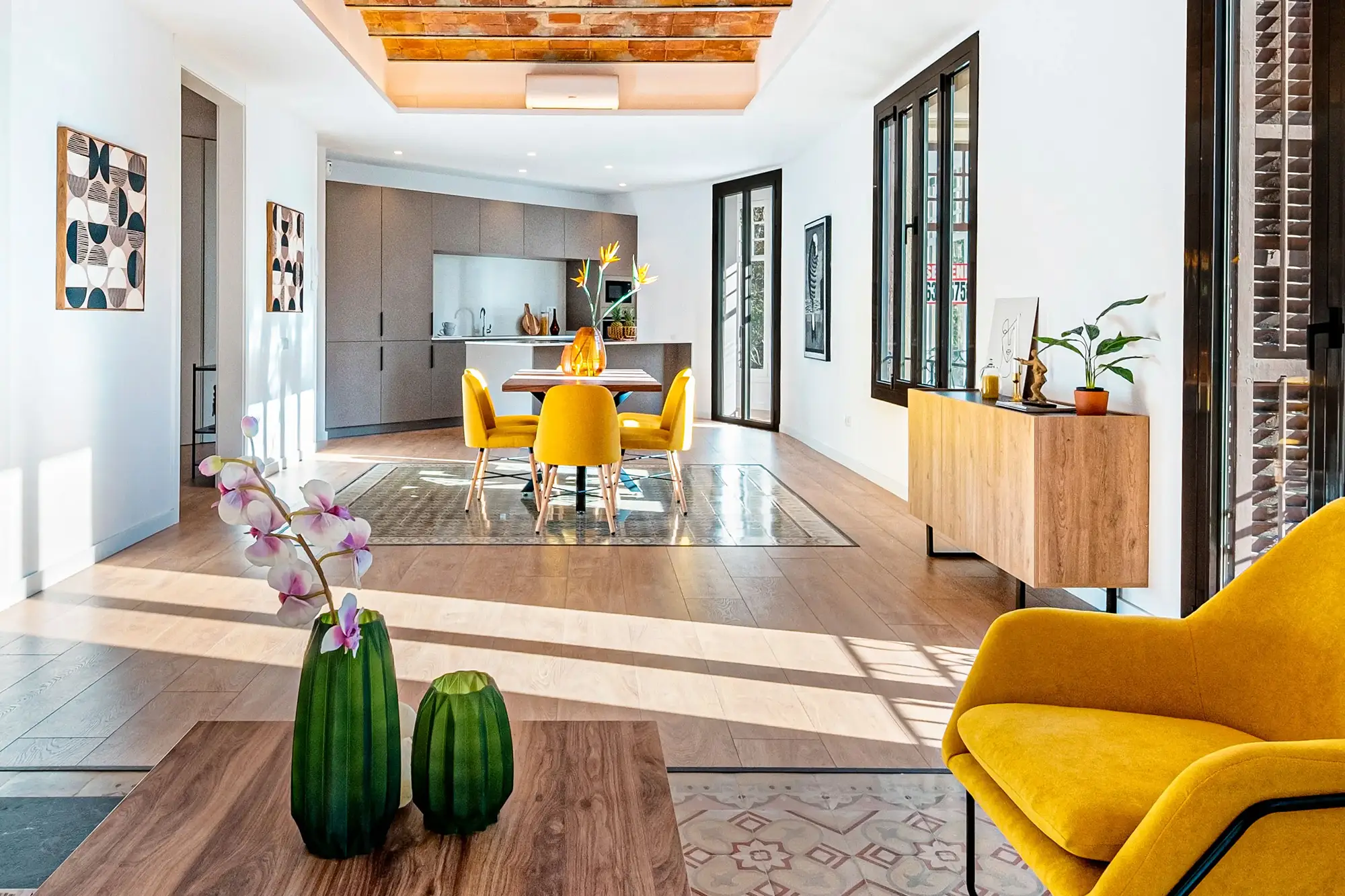 Un salón con suelo hidráulico y un techo de boveda en un piso modernista con muebles de madera y tonos amarillos