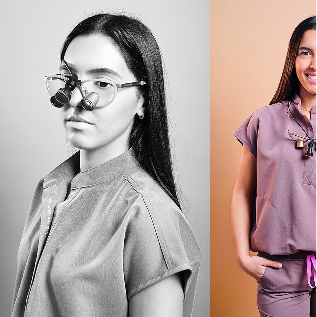 Side profile studio portrait of a woman with long dark hair wearing translucent glasses, photographed against a soft beige background.