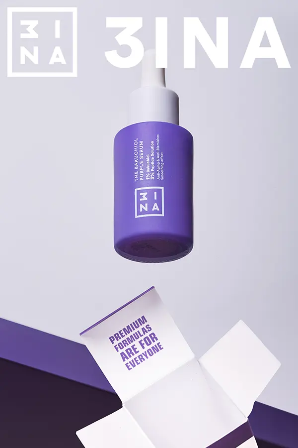 Serum facial ZINA en frasco morado suspendido sobre su caja abierta, fotografía de producto minimalista con fondo claro y estética premium.