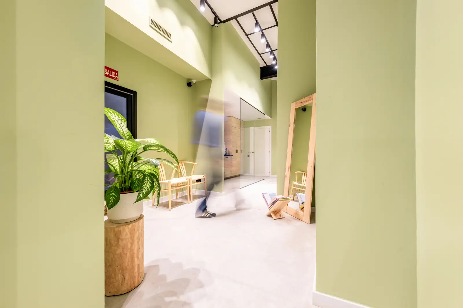 Pasillo interior de clínica dental moderna con paredes verdes y luz natural