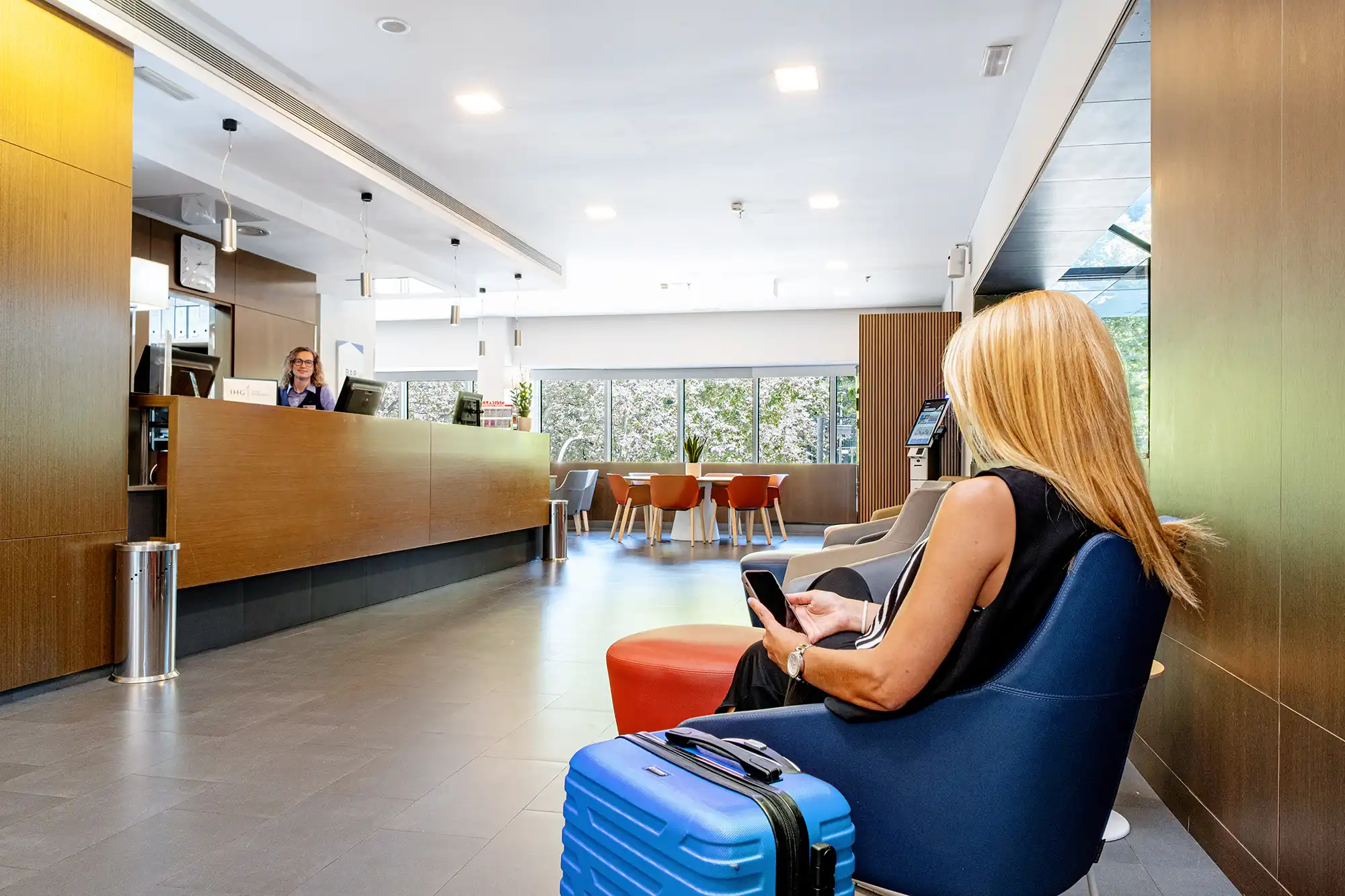 Huésped con una maleta esperando en la recepción de un hotel.