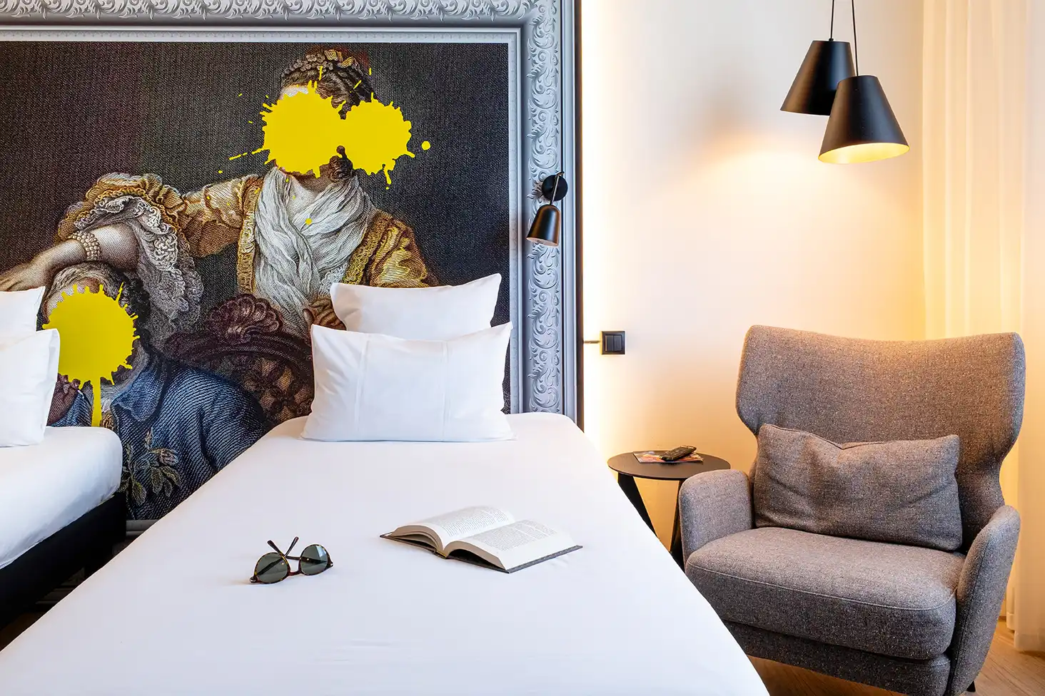 Detalle de una habitación con cama, sillón y decoración floral en el Ibis Styles Barcelona Sant Joan Despí.