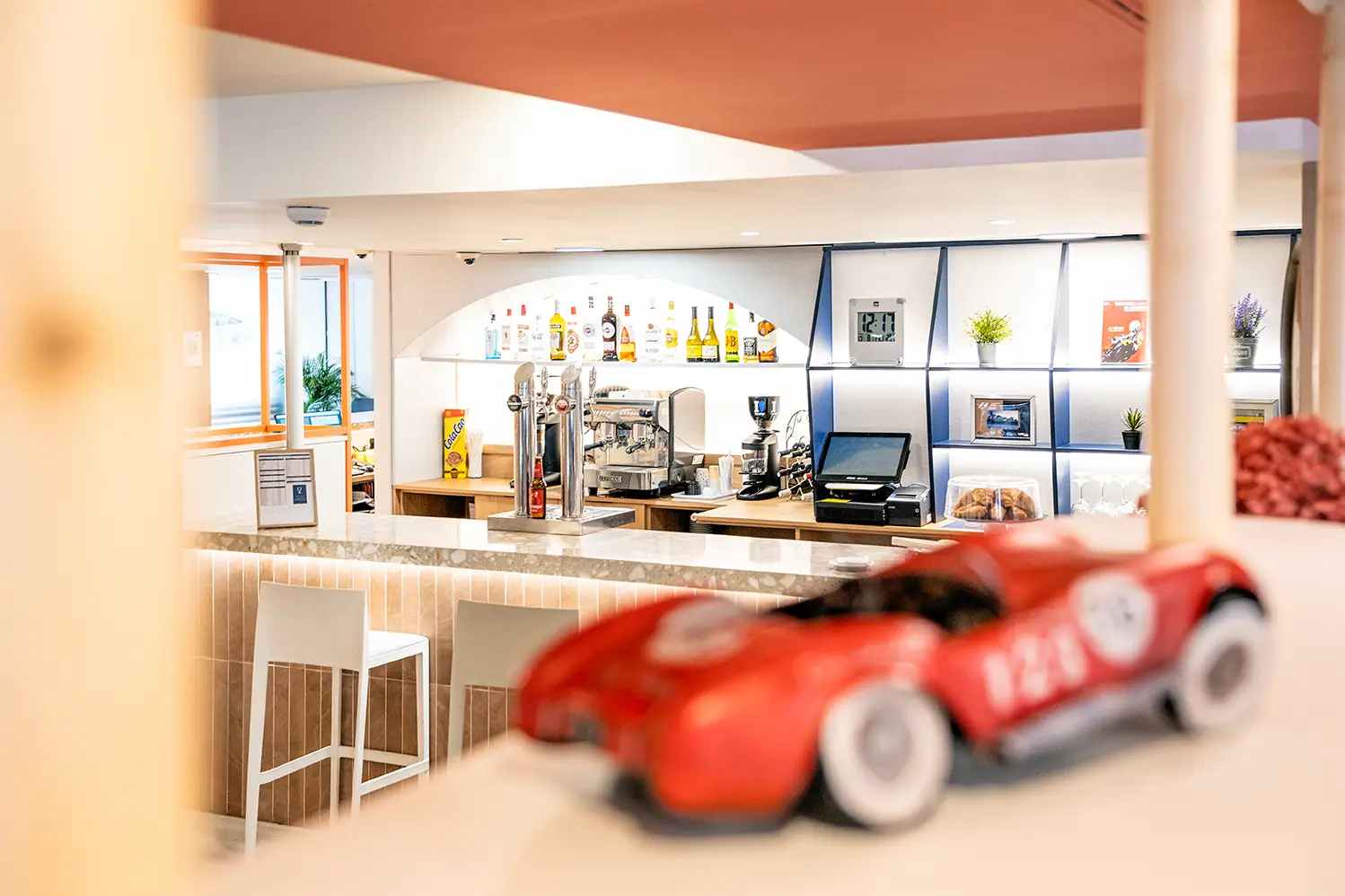 Fotografía de detalle del nuevo bar del Holiday Inn Express Barcelona Montmeló, con coche decorativo rojo en primer plano.