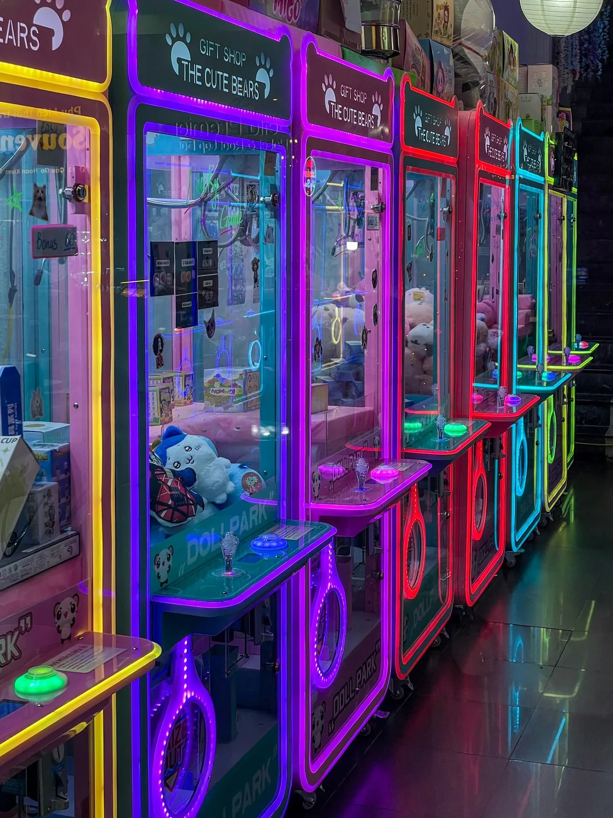 A row of neon-lit arcade claw machines on a venue floor