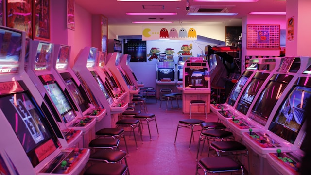 Row of retro arcade cabinets in a pink-lit game room