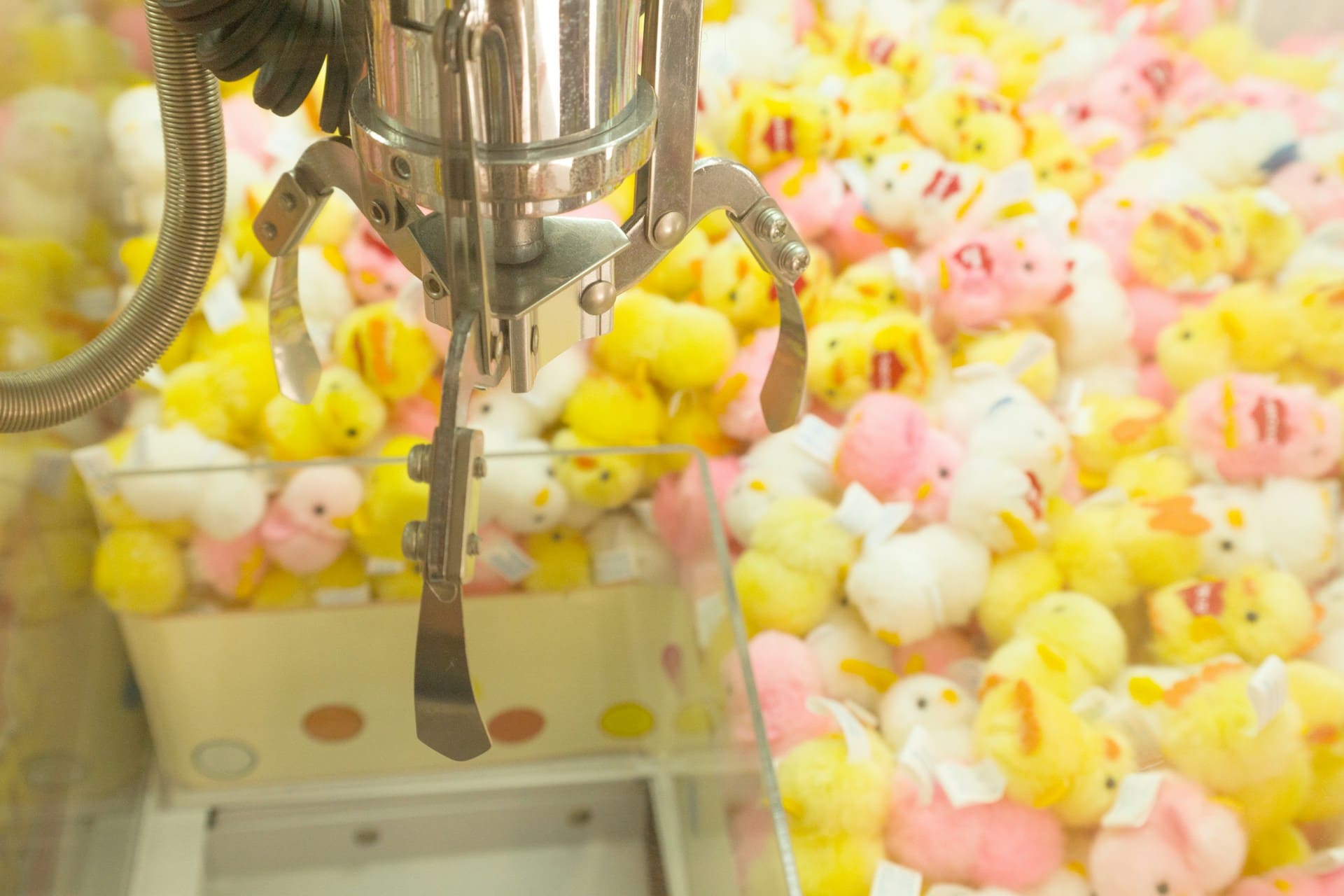 Macchina con artiglio piena di peluche a forma di pulcino gialli e rosa