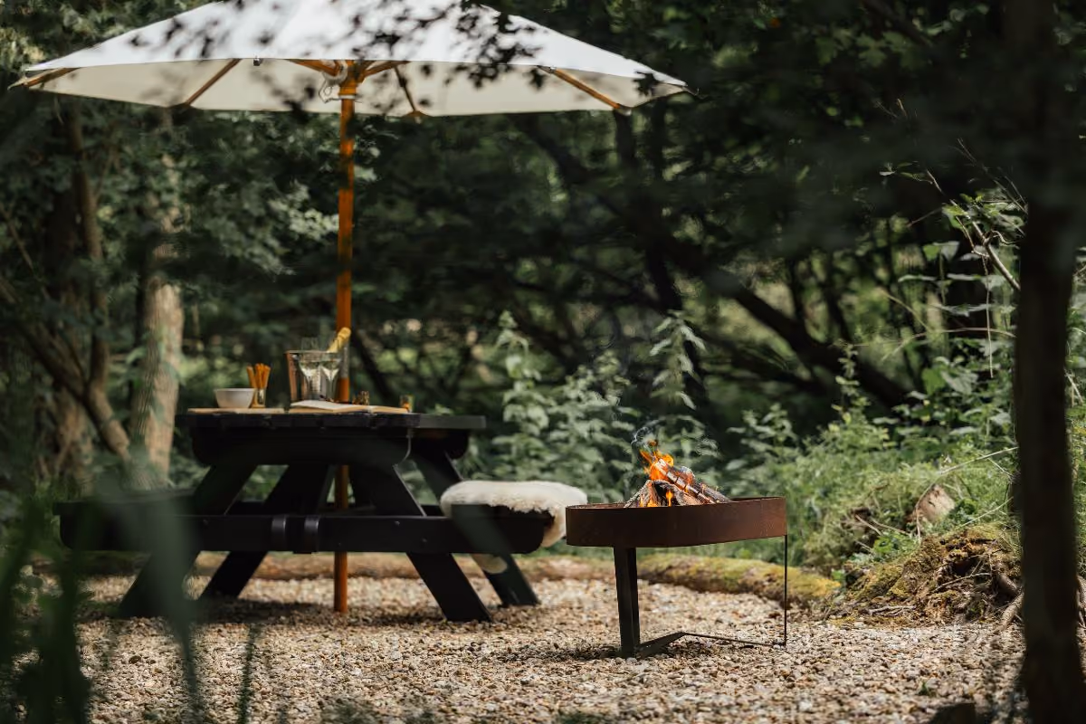Picnic bend and umbrella with fire pit at the Camping Pods