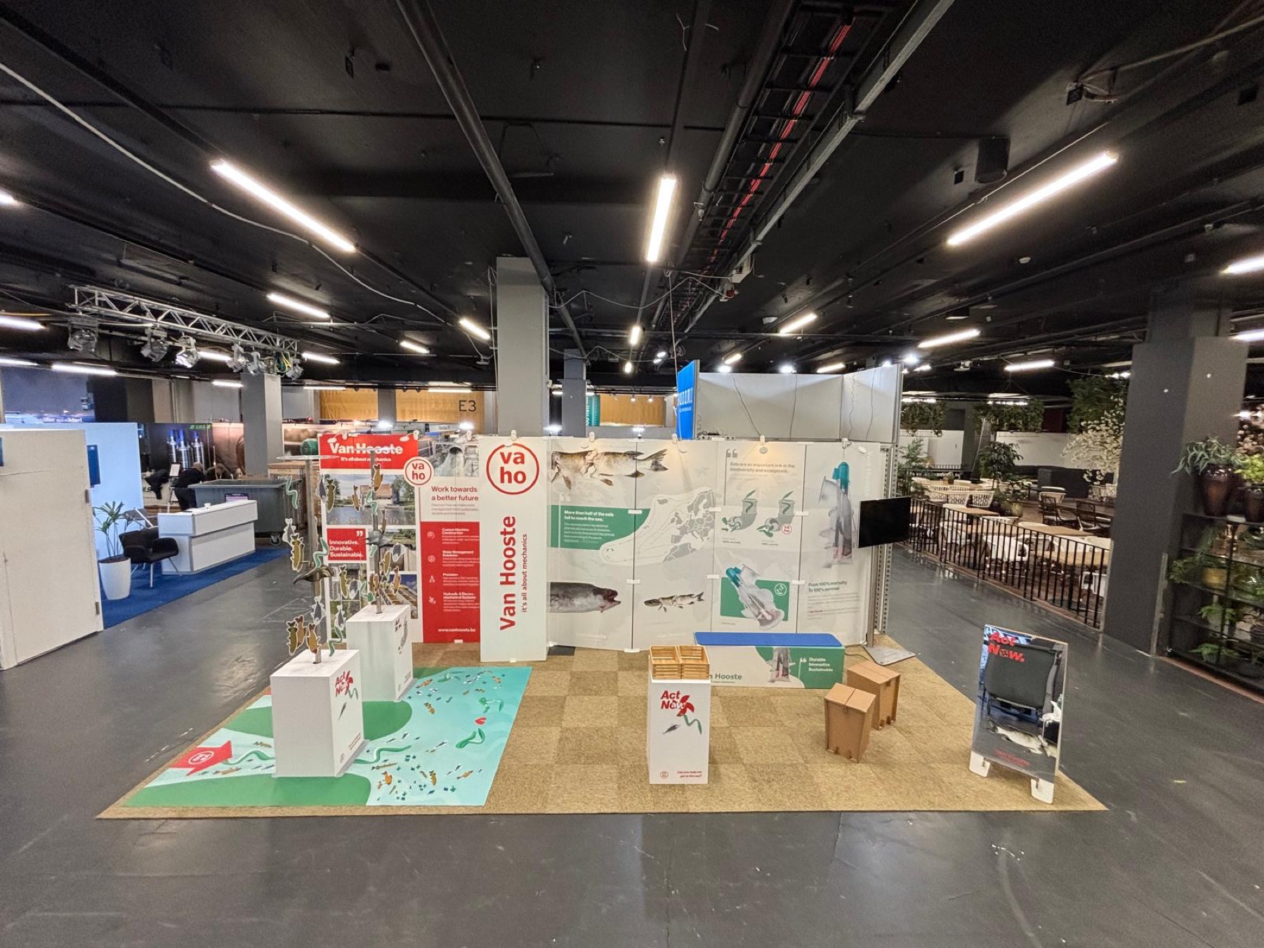 Wide shot of Van Hooste exhibition booth with fish mobiles, water management graphics, and interactive displays