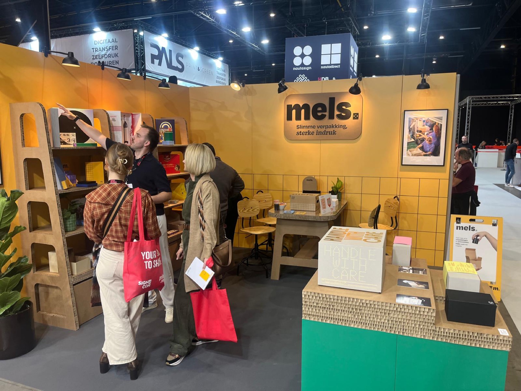Vibrant yellow trade show booth for Mels packaging company with corrugated cardboard displays and interactive elements