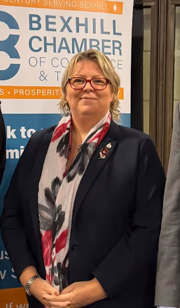 Tracy Love, President of The Bexhill Chamber of Commerce, standing in front of a banner.