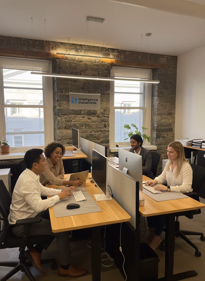 Diverse Industrial Intelligence team working in a bright office in the Old Port of Montreal, collaborating on manufacturing data and AI projects in front of their screens.