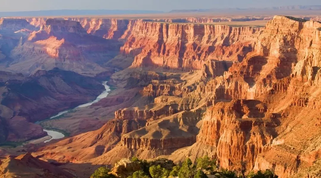 Arizona’s Grand Canyon with dramatic red rock formations and the Colorado River carved through the canyon floor.