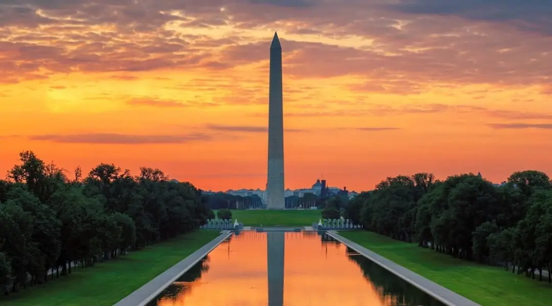 Washington, D.C. skyline featuring the Washington Monument and Reflecting Pool at sunset on the National Mall.