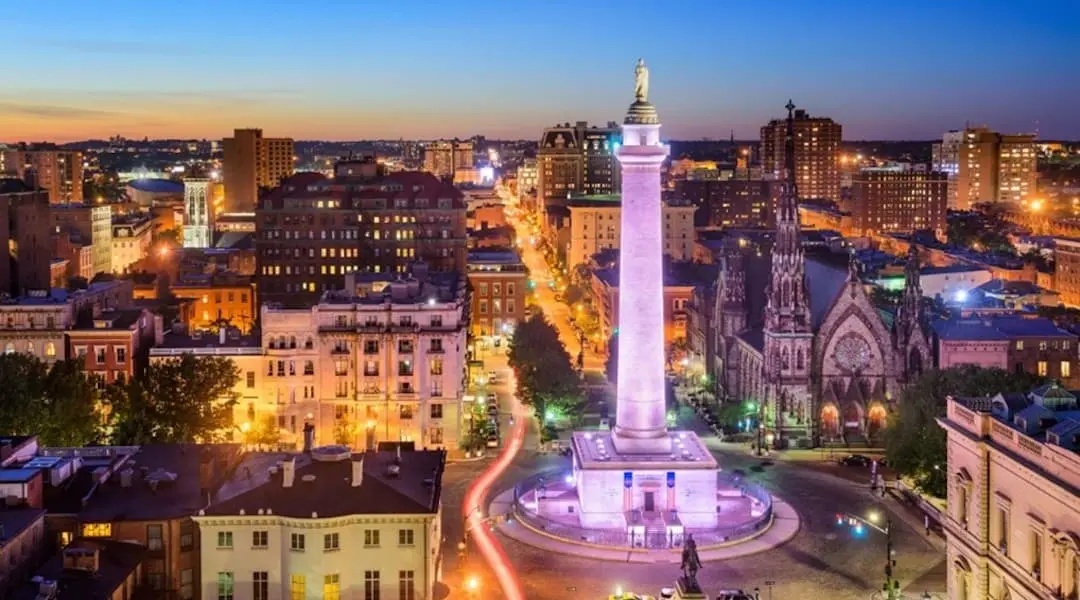 Maryland cityscape showing Baltimore’s Mount Vernon neighborhood with the Washington Monument illuminated at dusk.