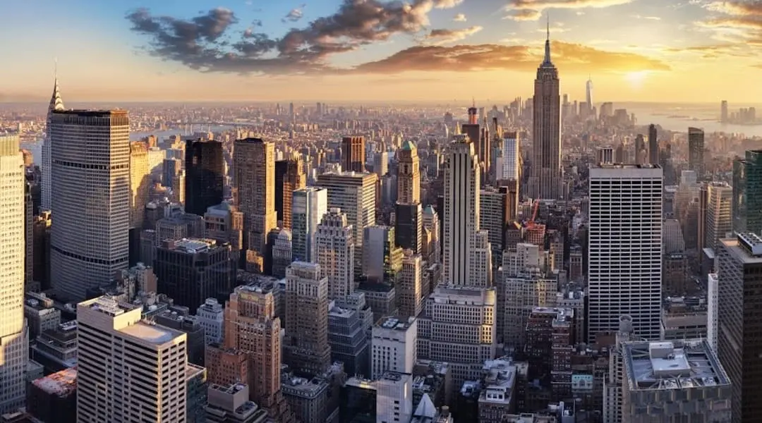New York City skyline with Midtown Manhattan skyscrapers and the Empire State Building at sunset, highlighting the state’s iconic urban landscape.
