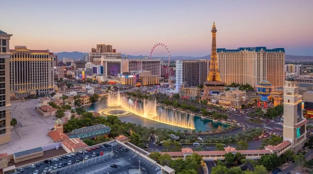 Nevada cityscape showing the Las Vegas Strip with the Bellagio fountains and iconic resort landmarks at sunset.