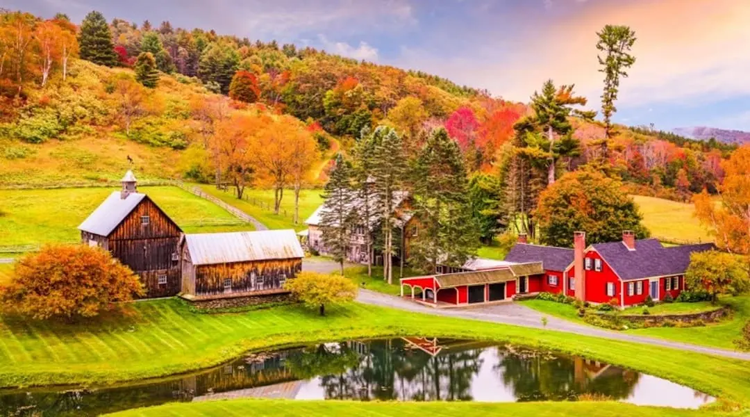 Vermont countryside featuring a traditional farm, red barns, and fall foliage, highlighting the state’s scenic rural landscape.