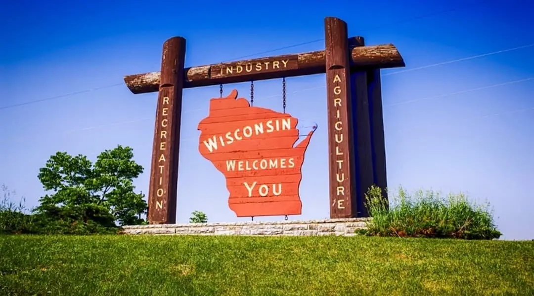 Wisconsin welcome sign with state outline and recreation, industry, and agriculture pillars, symbolizing Wisconsin’s economic landscape.