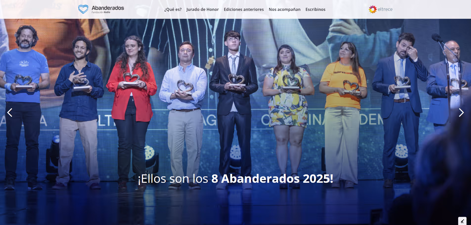Eight people standing on stage holding heart-shaped awards, caption reads 'They are the 8 Abanderados 2025!'