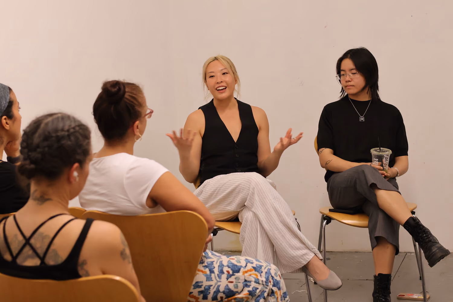 Screening: Erika Choe and Colby Lamson-Gordon: two people sit and talk in front of a seated audience, one smiling and gesturing, the other holding a cup.