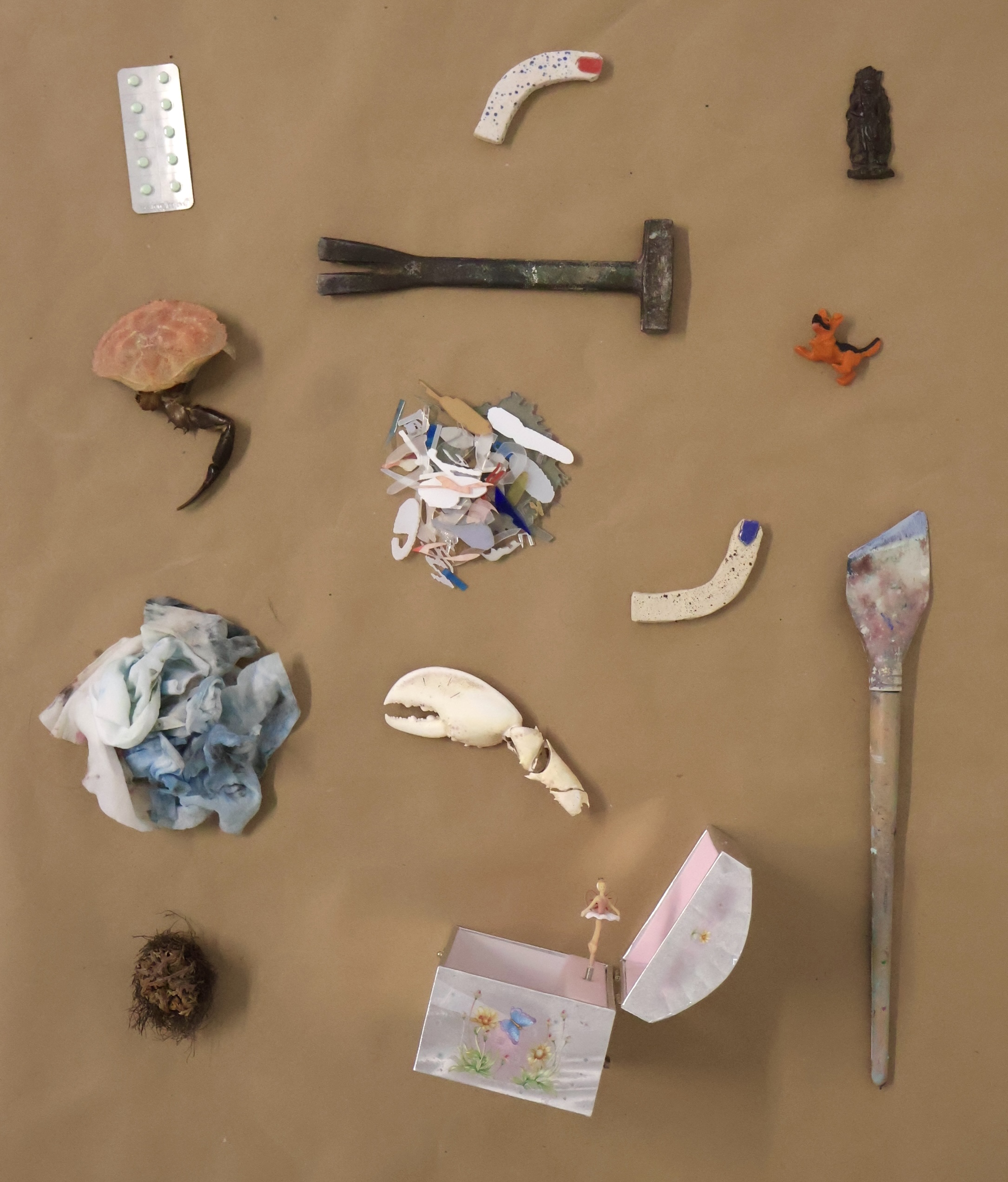 Collected Objects from Season III, 2026 Artists-in-Residence: found objects, including a hammer, claw, brush, and small box, laid out on brown paper.