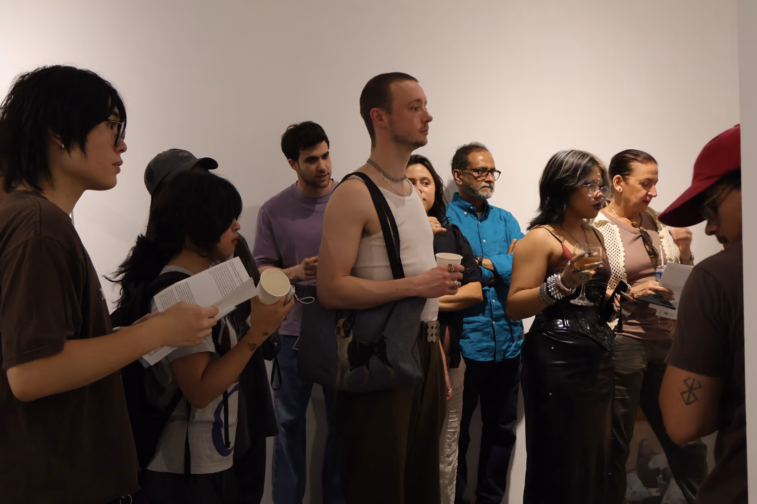 NARS Spring Open Studios 2026: a crowd of visitors holding drinks and papers stands together in a white gallery.