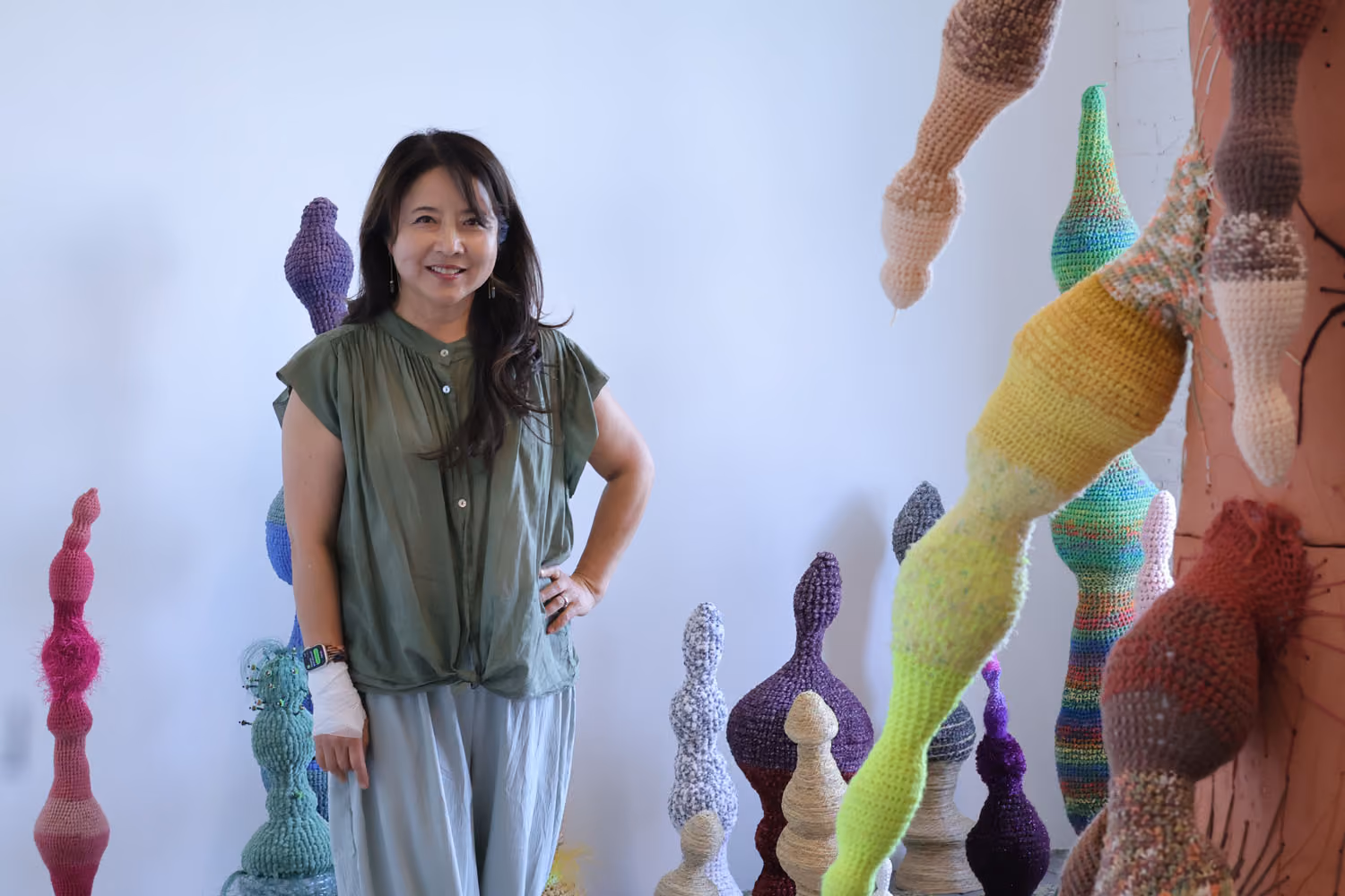 NARS Spring Open Studios 2026: a woman stands among tall crocheted sculptures in bright, multicolored yarn.