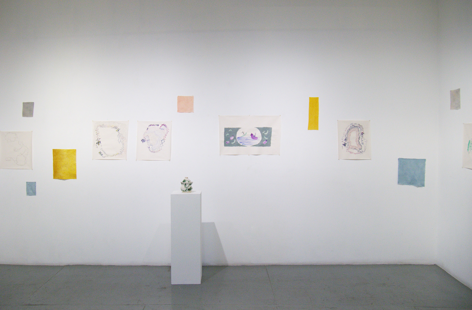 Yoshie Sugito, 2026. Image description: Installation view of BONE ASH, MEMORY HOLES, THE RECIPES: drawings, colored fabric swatches, and a ceramic vessel on a pedestal.