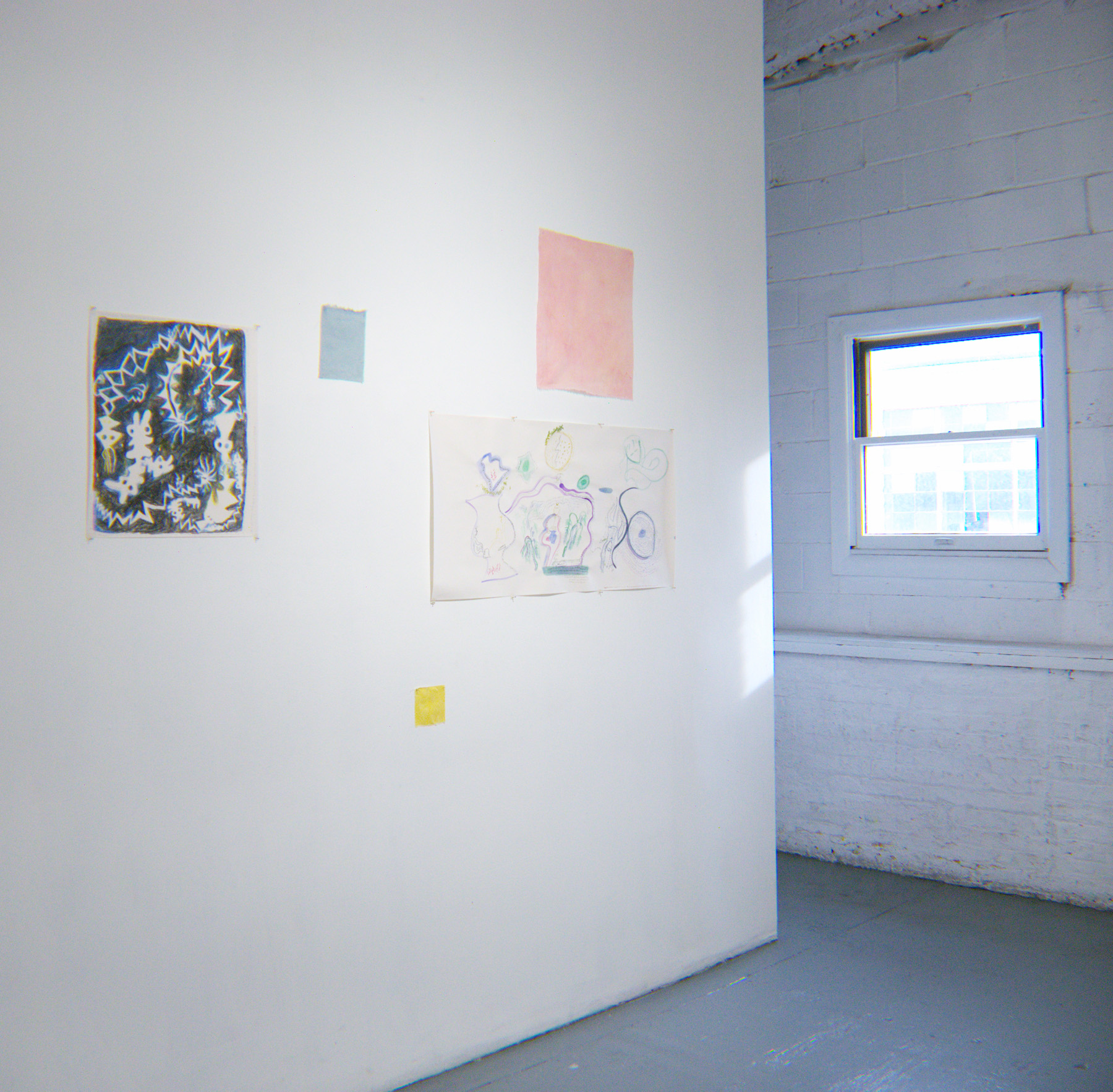Yoshie Sugito, 2026. Image description: Installation view of BONE ASH, MEMORY HOLES, THE RECIPES: artworks on paper and fabric mounted on a white wall beside a sunlit window.