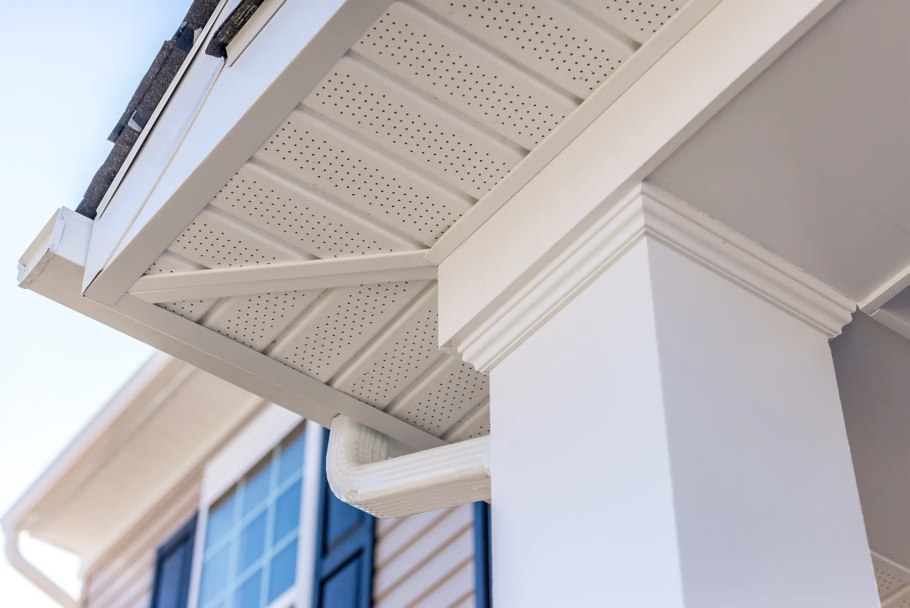 White perforated vinyl soffit panels on house eaves with decorative crown molding.