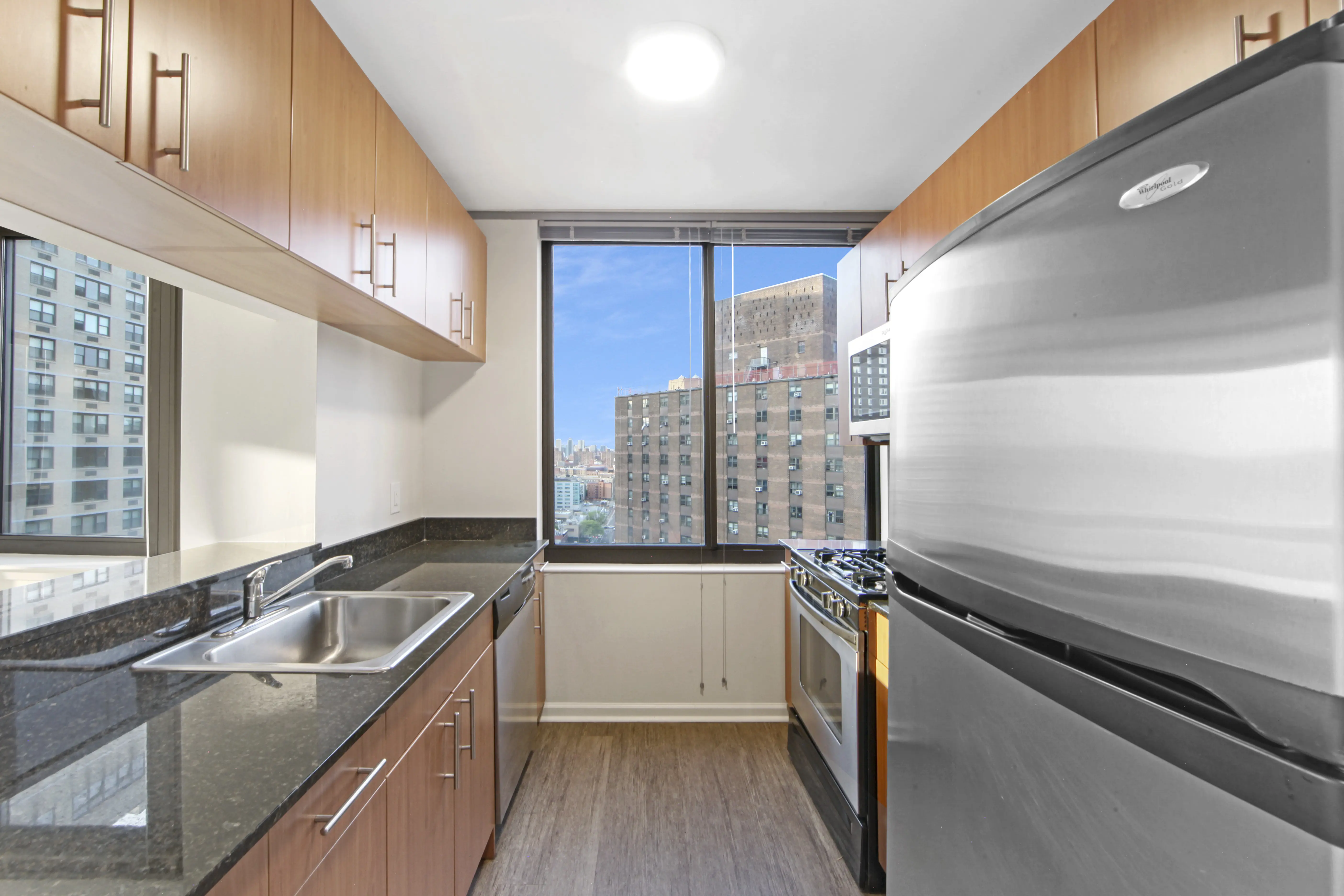 A modern kitchen featuring stainless steel appliances and a panoramic view of the city skyline through large windows.